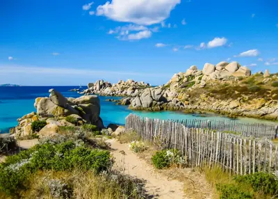 a beach with rocks and a wooden fence at Domaine de Licetto in Bonifacio