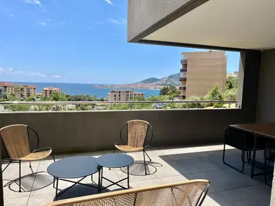 a balcony with chairs and tables and a view of the ocean at T2 Ajaccio vue mer in Ajaccio