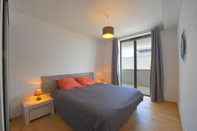 a bedroom with a bed with two red pillows and a window at Bel appartement vue mer Porto Vecchio in Porto-Vecchio