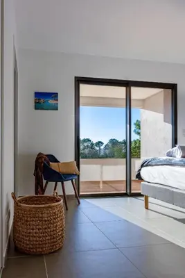 a bedroom with a bed and a chair and a window at Hotel Calarossa Bay Resort in Porto-Vecchio