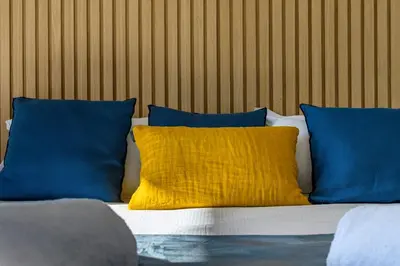 a bed with blue and yellow pillows on it at Hotel Calarossa Bay Resort in Porto-Vecchio