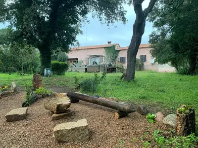 a garden with rocks and a house in the background at Chez Chris Mare & Macchia in Porto-Vecchio