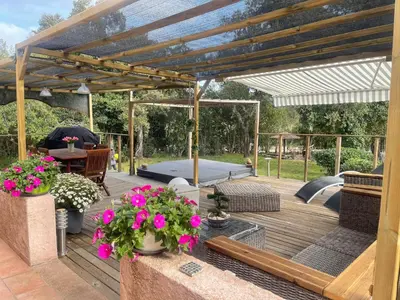 a wooden deck with a pergola with pink flowers at Chez Chris Mare & Macchia in Porto-Vecchio