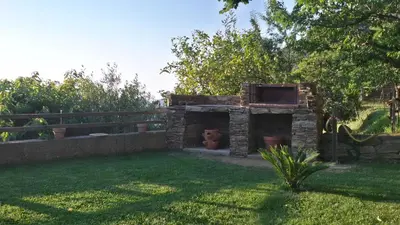 a garden with a stone structure in the grass at Maison 4 Pers - Vue mer et vignoble exceptionnelle in Poggio-dʼOletta