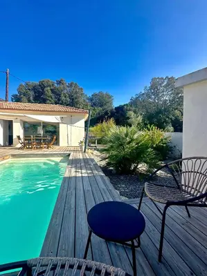 a wooden deck with chairs and a swimming pool at VILLA JUWEN in Oletta