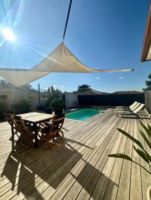 a patio with a table and chairs on a wooden deck at VILLA JUWEN in Oletta