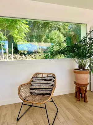 a rattan chair in a room with a potted plant at VILLA JUWEN in Oletta