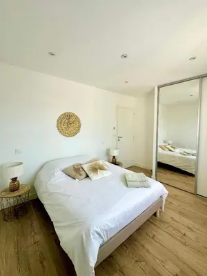 a white bedroom with a large bed and a mirror at VILLA JUWEN in Oletta