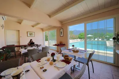 a restaurant with white tables and chairs and a pool at Terracorse in Figari