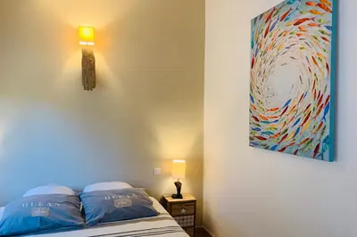 a bedroom with a bed with a painting on the wall at Charmante villa 2 chambres les pieds dans l'eau Bonifacio in Bonifacio