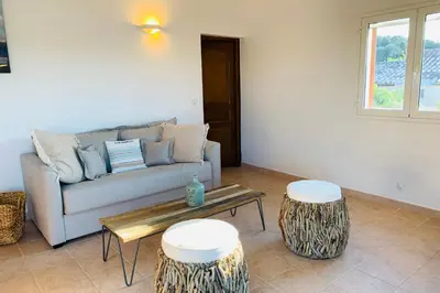 a living room with a couch and two stools at Charmante villa 2 chambres les pieds dans l'eau Bonifacio in Bonifacio