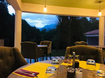 a restaurant with a table and chairs and a large window at Hôtel Cantu di Fiumu in Zonza