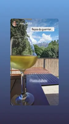 a glass of white wine sitting on a table at Hôtel Cantu di Fiumu in Zonza