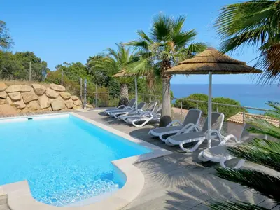 a pool with chairs and an umbrella and the ocean at Holiday Home Villa Ottavi by Interhome in Sainte-Lucie de Porto-Vecchio