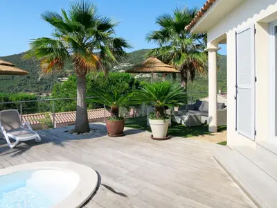 a patio with palm trees and a chair at Holiday Home Villa Ottavi by Interhome in Sainte-Lucie de Porto-Vecchio