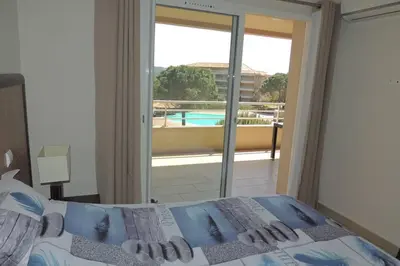 a bedroom with a bed with a view of a pool at Appartement vue piscine dans résidence de standing in Porto-Vecchio