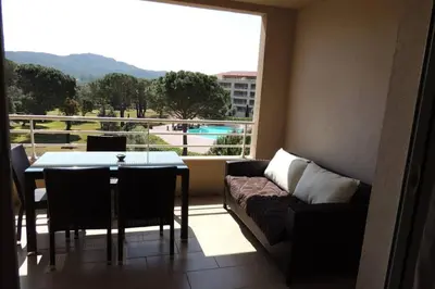a living room with a couch and a table and a window at Appartement vue piscine dans résidence de standing in Porto-Vecchio