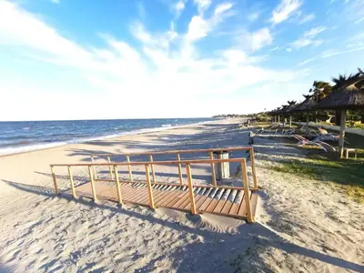 a wooden bench sitting on the beach near the ocean at Résidence San Pellegrino in Folelli