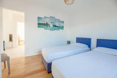 two beds in a room with white walls and wooden floors at Casa Fiumu Oso in San-Gavino-di-Carbini