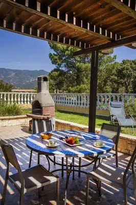 a table and chairs on a patio with a stove at Résidence du pont de l'Oso in Porto-Vecchio