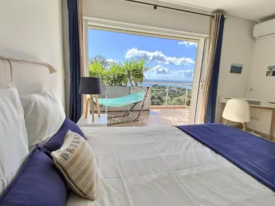 a bedroom with a bed and a view of the ocean at VILLA CARAMONTINU SERENA à Pinarello, proche plage, vue mer, piscine chauffée in Zonza