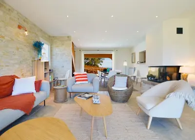 a living room with white furniture and a brick wall at VILLA CARAMONTINU SERENA à Pinarello, proche plage, vue mer, piscine chauffée in Zonza