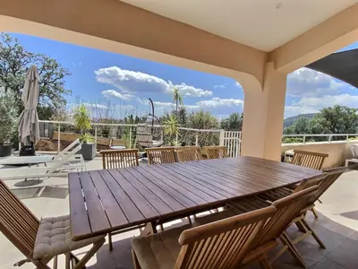 a patio with a wooden table and chairs at VILLA CARAMONTINU SERENA à Pinarello, proche plage, vue mer, piscine chauffée in Zonza