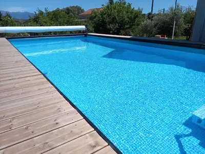 a swimming pool with a wooden deck and a blue swimming pool at L'Alivu in Ajaccio