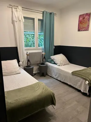 a bedroom with two beds and a window at Chez Muriel in Porto-Vecchio