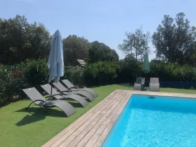 a group of lounge chairs with an umbrella and a pool at Chez Muriel in Porto-Vecchio