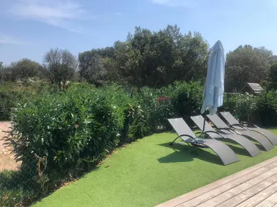 a row of chairs with an umbrella and grass at Chez Muriel in Porto-Vecchio
