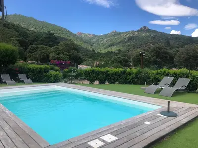 a swimming pool with chairs and mountains in the background at Chez Muriel in Porto-Vecchio