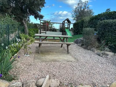 a park bench with a playground in a garden at Chez Muriel in Porto-Vecchio