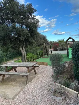 a picnic table in a garden with a playground at Chez Muriel in Porto-Vecchio