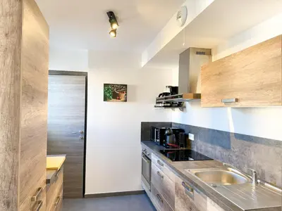a kitchen with wooden cabinets and a sink at Fronte di Mare 2 chambres vue mer - 1 in Propriano