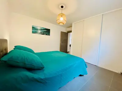 a bedroom with a blue bed and a light at Fronte di Mare 2 chambres vue mer - 1 in Propriano