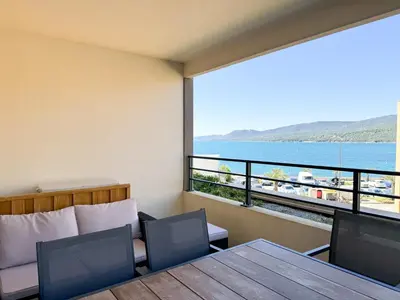 a room with a table and chairs and a view of the water at Fronte di Mare 2 chambres vue mer - 1 in Propriano