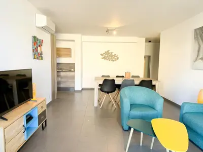 a living room with a tv and a table and chairs at Fronte di Mare 2 chambres vue mer - 1 in Propriano
