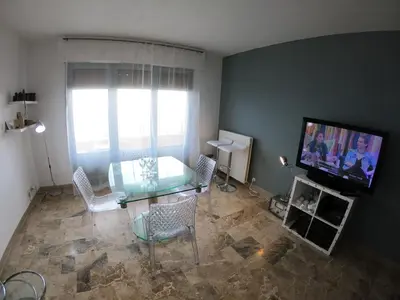 a living room with a table and a flat screen tv at PASSERELLE DU MARIN in Ajaccio