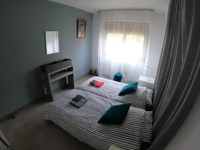 a bedroom with a bed with green pillows and a window at PASSERELLE DU MARIN in Ajaccio