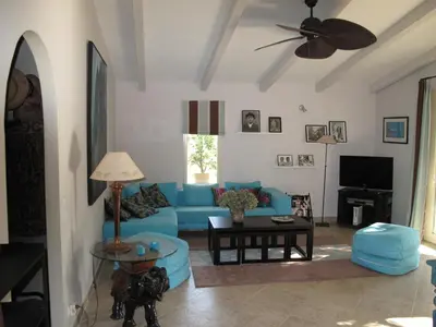 a living room with a blue couch and a ceiling fan at Domaine Panciarella in Saint-Florent