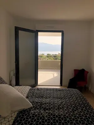 a bedroom with a bed and a large sliding glass door at Bel appartement f3 vue sur le golfe d’ajaccio in Ajaccio