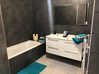a bathroom with a white sink and a bath tub at Bel appartement f3 vue sur le golfe d’ajaccio in Ajaccio