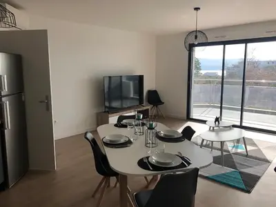 a dining room with a white table and a tv at Bel appartement f3 vue sur le golfe d’ajaccio in Ajaccio
