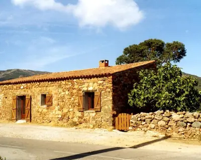 a stone building with a stone wall and a tree at Maison de caractère, pierre sèche, Galéria, pour 2 in Galeria