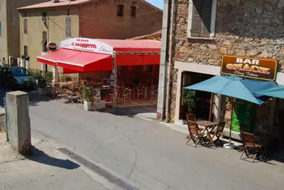 an outdoor restaurant with chairs and umbrellas on a street at Maison de caractère, pierre sèche, Galéria, pour 2 in Galeria