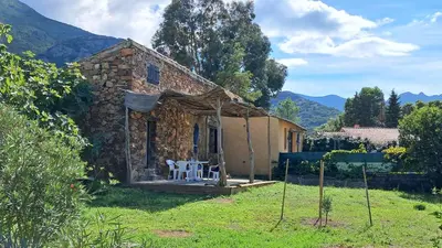 a small stone house with a white chair in a yard at Maison de caractère, pierre sèche, Galéria, pour 2 in Galeria