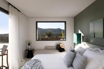 a bedroom with a white bed and a large window at Villa EVA, vue mer et montagne, plage à pieds in Sainte-Lucie de Porto-Vecchio