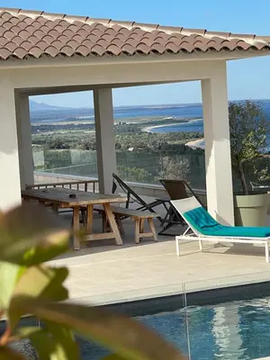 a patio with a table and chairs and a pool at Villa Mare d'argentu La solenzara in Sari Solenzara