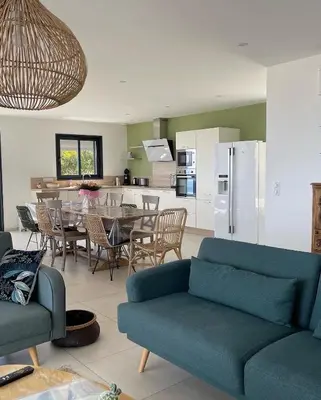a living room with a blue couch and a kitchen at Villa Mare d'argentu La solenzara in Sari Solenzara